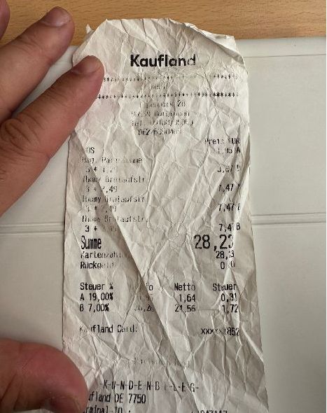 Zerknitterter Kassenbon auf Thermopapier mit teils aufgelösten Druckbereichen